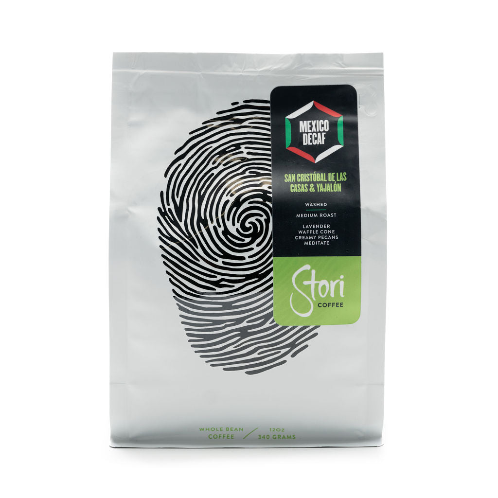 This picture shows an image of the front of our Single Origin Decaf Mexico Coffee Bag. The bag is white with a black thumb print to symbolize our global connection. 