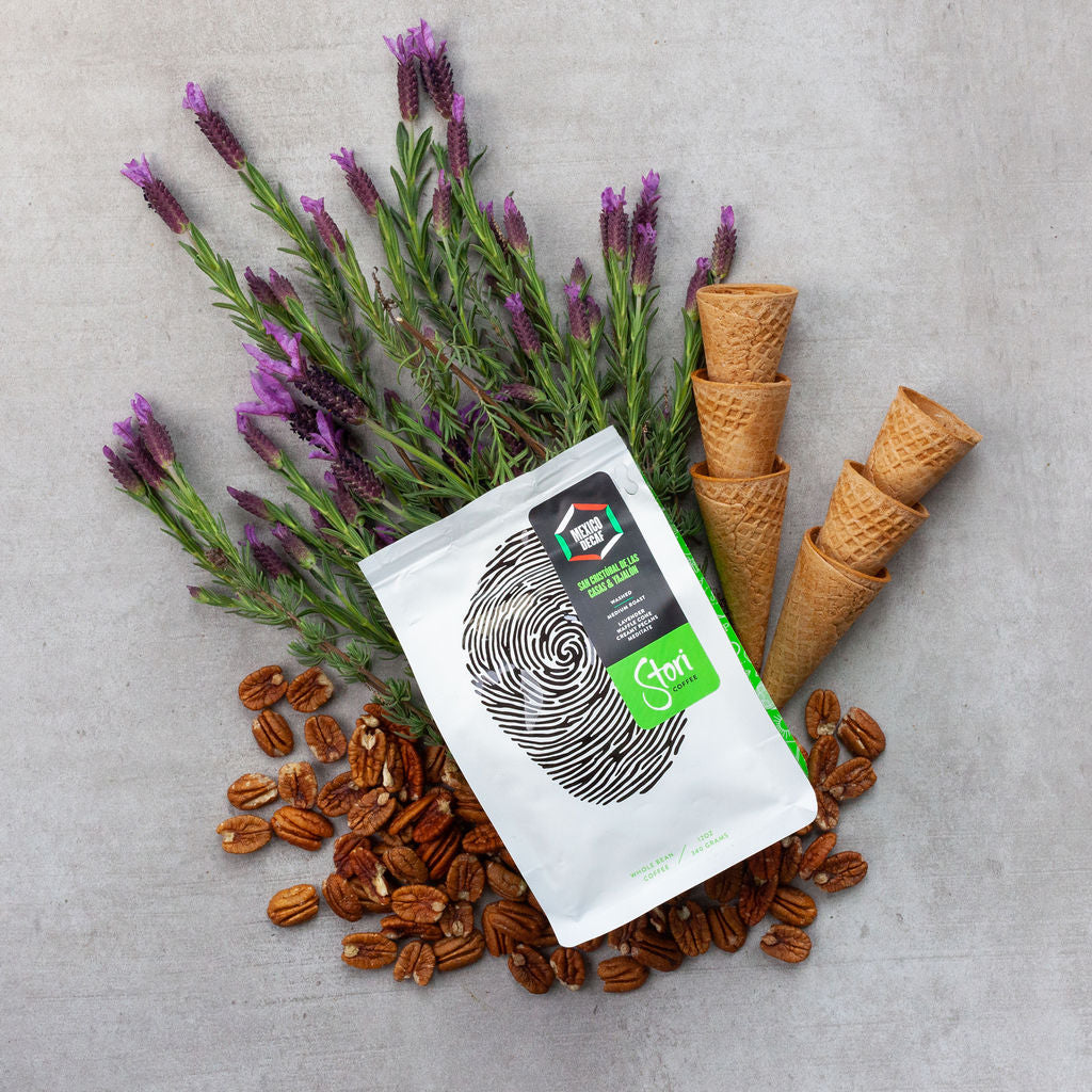 This pin shows the flavor profile of our Ethically Sourced Single Origin Decaf Coffee from Mexico. In it the coffee bag, with an image of a thumbprint that signifies our global connection, sits on top of fresh lavender, ice cream cones, and pecans. 